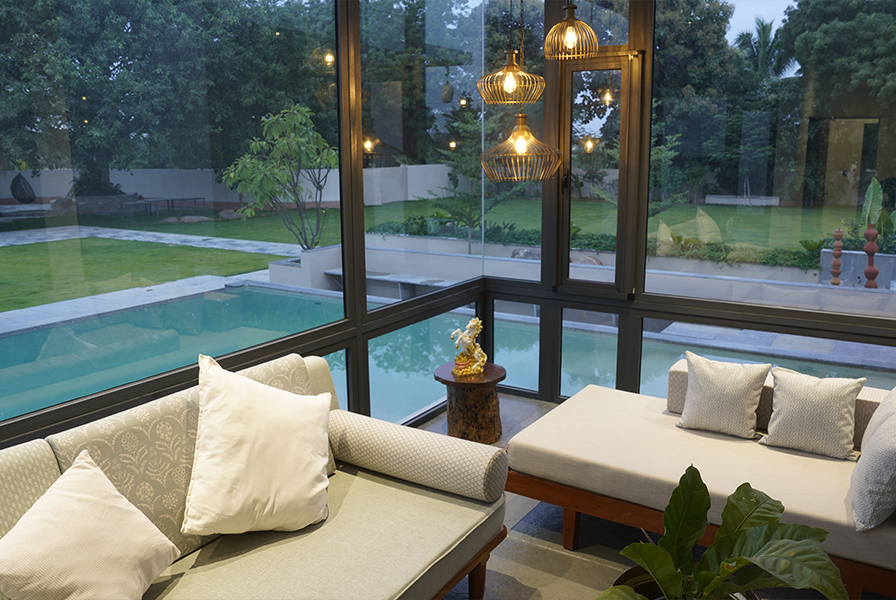 A living room with floor-to-ceiling glass windows overlooking a pool